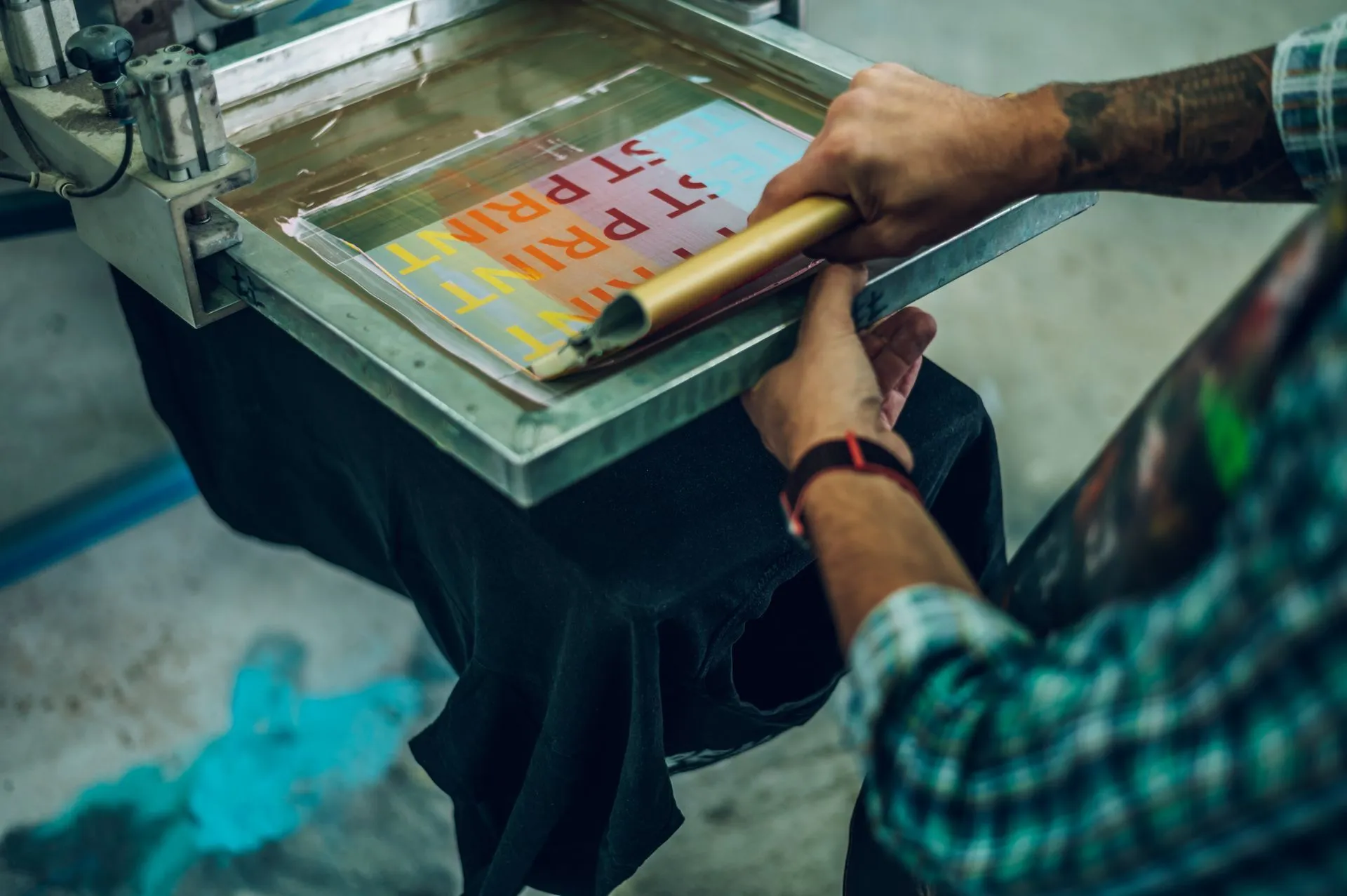 Worker pressing an ink frame on a screen printing machine